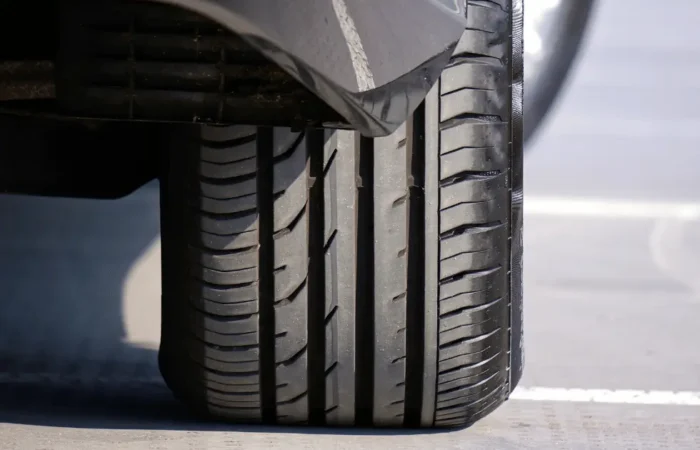 Close-up of a car's front tyre showing the tread depth and grooves used to maintain grip and channel water.